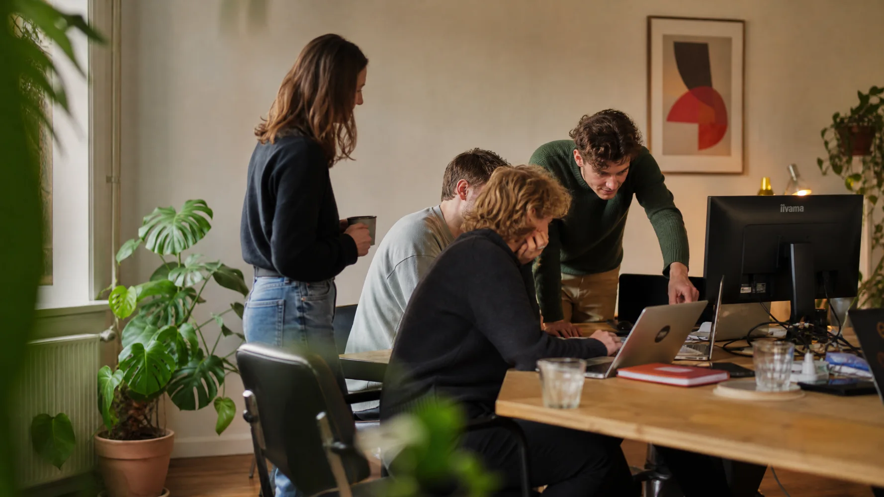 Het team van Zorg op Koers werkt samen achter een laptop op kantoor in Amsterdam